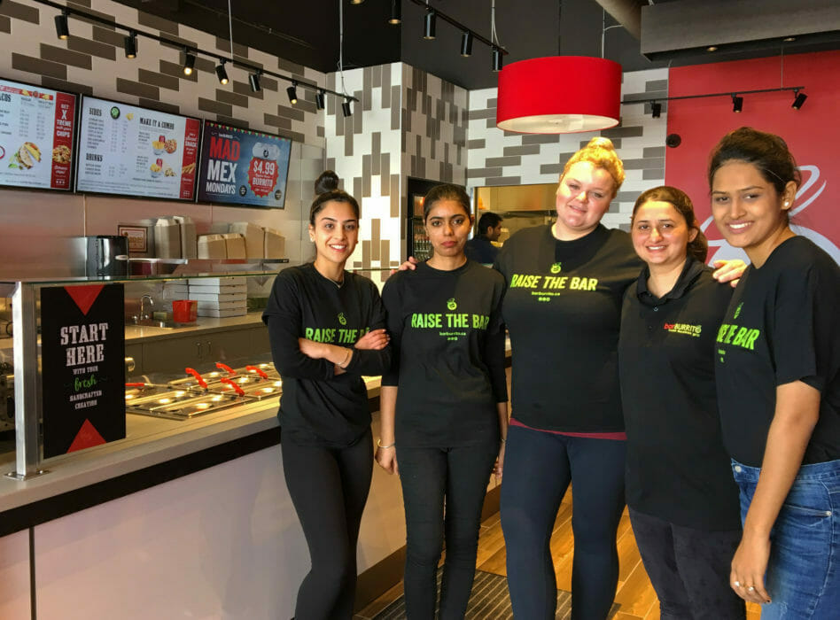 3 men and 2 women standing beside counter